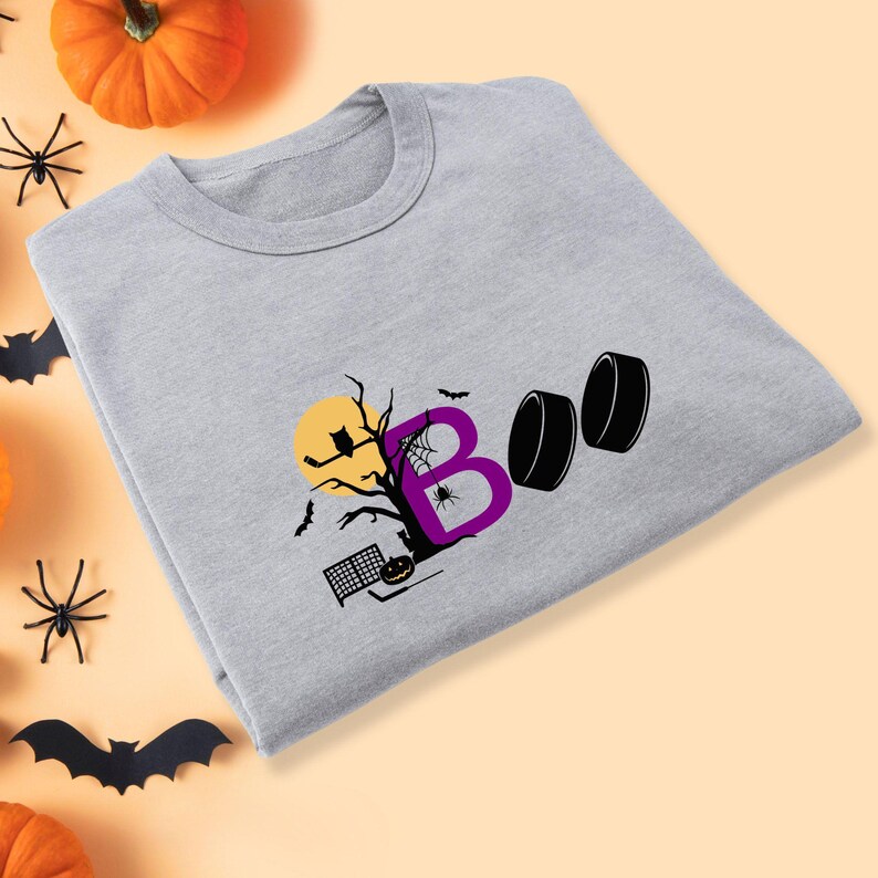 May include: Gray t-shirt with a purple "BOO" graphic featuring a spooky tree, a spider, a bat, and a hockey puck.
