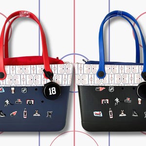 May include: Two black and white patterned tote bags with red and blue handles. The bags have a variety of hockey-themed charms attached to them. One bag has a black charm with the number 18 on it.