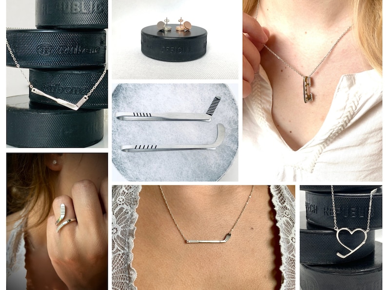 May include: A set of hockey-themed jewelry, including a necklace with a hockey stick pendant, a ring with a hockey stick design, and a pair of earrings with a hockey puck design. The jewelry is displayed on a black hockey puck.