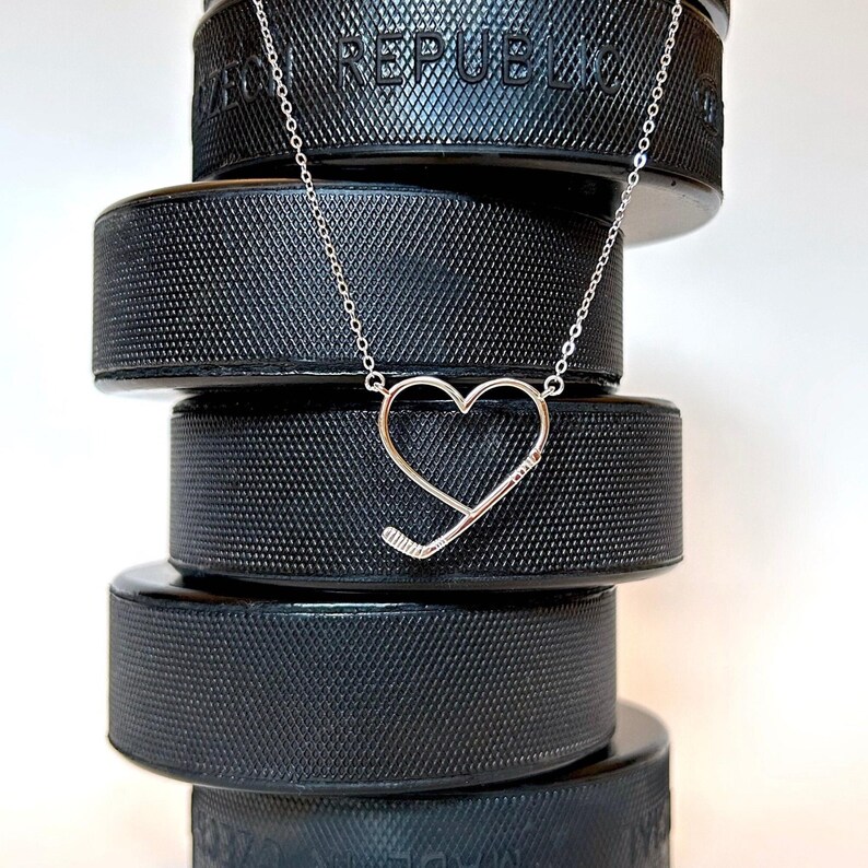 Sterling silver necklace in the shape of a heart with a hockey stick shaped in to the heart design.