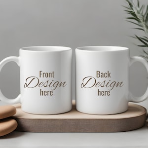 May include: Two white ceramic mugs with black text. The mug on the left says "Front Design here" and the mug on the right says "Back Design here". The mugs are on a wooden coaster.