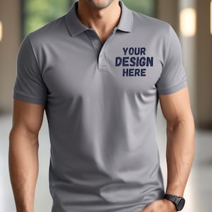 May include: A gray polo shirt with short sleeves and a button-up collar. The shirt has the text "YOUR DESIGN HERE" printed on the front.