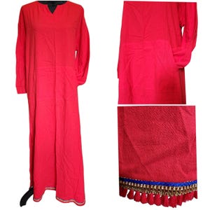 May include: A long, flowing red dress with long sleeves and a V-neckline. The hemline is adorned with blue, gold, and red tassels. The dress is made of a lightweight fabric.