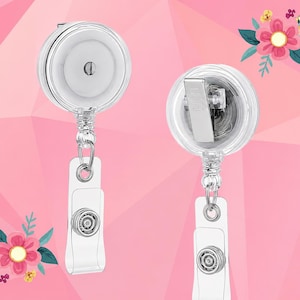 May include: Two clear plastic badge reels with retractable cords and metal belt clips on the back. Each reel features a white circular center and a clear plastic strap with a metal snap button closure at the bottom for attaching identification cards.