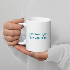 May include: White ceramic coffee mug with a teal design that says "What would your love coach do?"