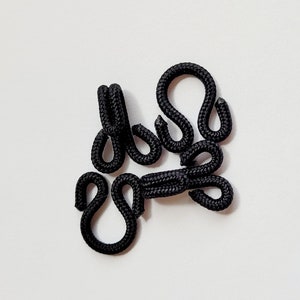 May include: Black elastic loops for sewing or crafting. The loops are connected together in a cluster.