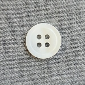 Pode incluir: Um bot&atilde;o de pl&aacute;stico branco com quatro furos.