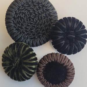May include: Four decorative buttons in black, brown, and green. The buttons are round and have a raised, textured design.