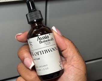 May include: A brown glass bottle with a black dropper, labeled "Wormwood Tincture" by Avaia Botanicals. The label also states "100% Organic" and the volume is 2 oz.