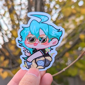 May include: A sticker of a cartoon character with blue hair, wearing round glasses and a black shirt with a star design. The character is sitting with their legs crossed and has a peace sign with their fingers.