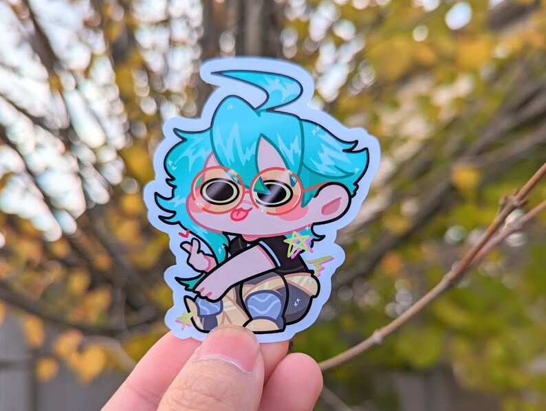 May include: A sticker of a cartoon character with blue hair, wearing round glasses and a black shirt with a star design. The character is sitting with their legs crossed and has a peace sign with their fingers.