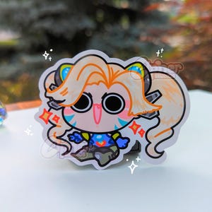 May include: A sticker of a cartoon character with long blonde hair, wearing a blue and yellow outfit. The character has large eyes and a wide smile. The sticker is on a white background with sparkles.