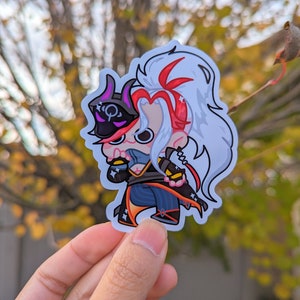 May include: A sticker featuring a cartoon character with white hair, a red and black outfit, and a black mask. The character is holding a weapon in their right hand and has a determined expression.