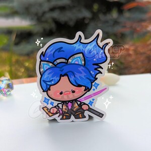 May include: A blue and white anime character sticker with a pink sword and sparkles. The character has blue hair and a white headband with cat ears.