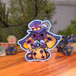 May include: A black and yellow cartoon character with a top hat and wings, holding three white and grey spheres. The character is on a wooden surface with several multi-coloured dice.