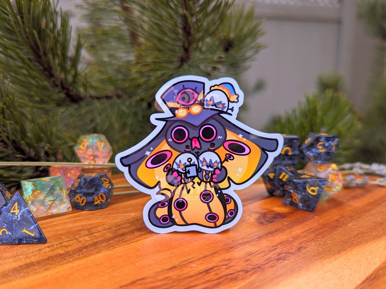 May include: A black and yellow cartoon character with a top hat and wings, holding three white and grey spheres. The character is on a wooden surface with several multi-coloured dice.