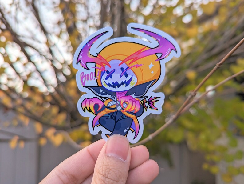May include: A sticker featuring a cartoon character with a pumpkin head, wearing a black and purple costume. The character has a wide grin and X-shaped eyes. The sticker has a white background and the word "Boo!" is written in pink letters.