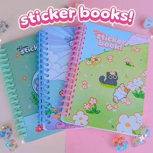 May include: Three spiral-bound sticker books with colourful covers. The covers feature illustrations of a cat, flowers, and other cute designs. The text "sticker books!" is displayed above the books. Dice are scattered around the books.