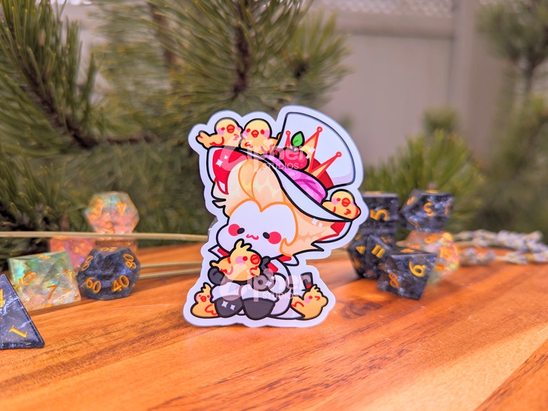 May include: A white sticker featuring a cartoon character wearing a red and white hat with a crown and holding a small yellow chick. The character is surrounded by other small yellow chicks.