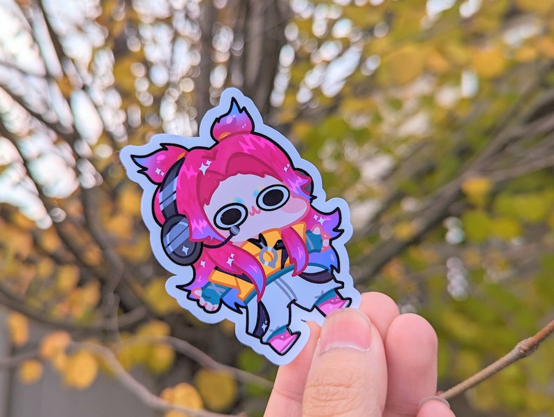 May include: A sticker featuring a cartoon character with pink hair, wearing headphones and a yellow jacket. The character has large eyes and a surprised expression.