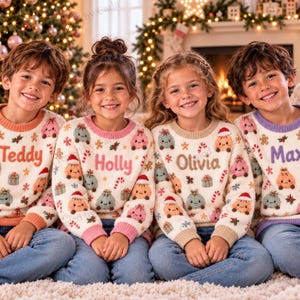 May include: Four long-sleeved jumpers featuring a cream base with a repeating pattern of gingerbread cookies, gift boxes, and candy canes. Each jumper is personalised with a name in the centre: Teddy, Holly, Olivia, and Max.