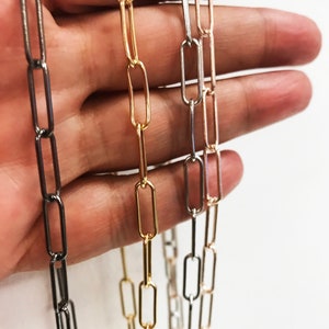 May include: Three chains of different colors: black, gold, and silver. Each chain is made of linked rectangular metal pieces.