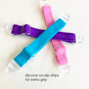 May include: Three silicone no-slip strips in pink, blue and purple. Each strip has a clear plastic buckle on each end. The text "silicone no-slip strips for extra grip" is written below the strips.