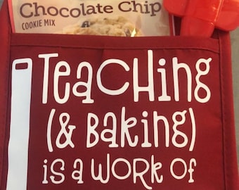 Op de afbeelding: Een rode ovenwant met een wit potlood en de tekst "Onderwijs (& Bakken) is een kwestie van hart". Een pak Betty Crocker Chocolate Chip Cookie Mix en een rode spatel zitten in de zak van de ovenwant.
