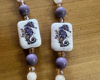 Cadena para gafas hecha a mano. Cuentas moradas y blancas con dije de caballito de mar.