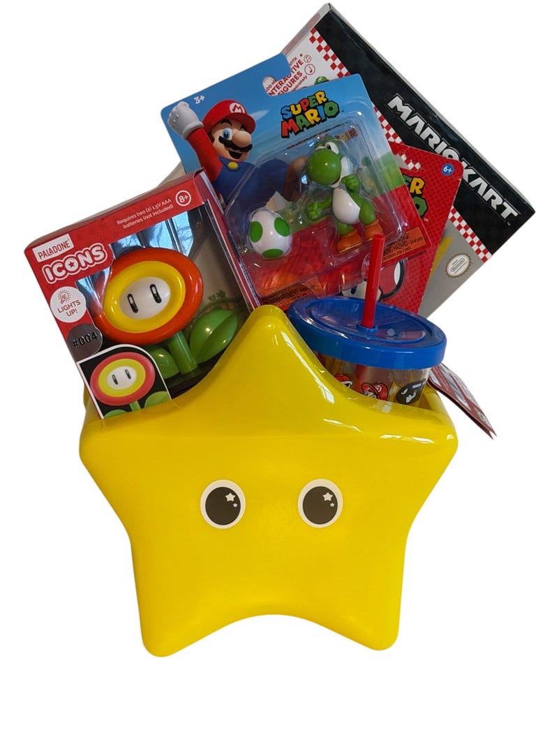 K&ouml;nnte beinhalten: Ein gelber sternf&ouml;rmiger Beh&auml;lter gef&uuml;llt mit Spielzeug und Waren zum Thema Super Mario. Enth&auml;lt eine Mario-Figur, eine Yoshi-Figur, ein Mario Kart-Spiel und ein Paladone Icons-Spielzeug. Ein blau-roter Becher mit Strohhalm ist ebenfalls sichtbar.