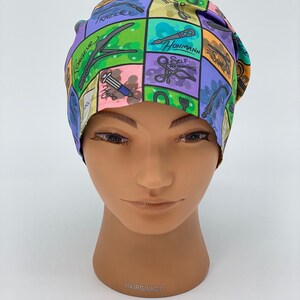 May include: A colorful surgical scrub hat with a variety of surgical instruments and tools printed on it. The hat is made of a soft, breathable fabric and is designed to be comfortable to wear for long hours.