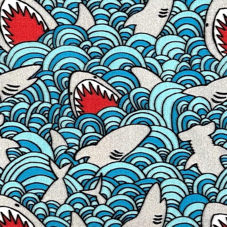 May include: A repeating pattern of cartoon sharks and ocean waves. The sharks are white with red mouths and sharp teeth. The waves are blue and white, creating a dynamic and playful design.