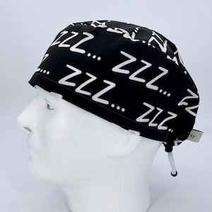May include: Black scrub hat with a white 'ZZZ' pattern. The hat has a drawstring.