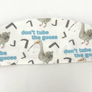 May include: White surgical scrub hat with a repeating pattern of geese and the text "don't tube the goose".