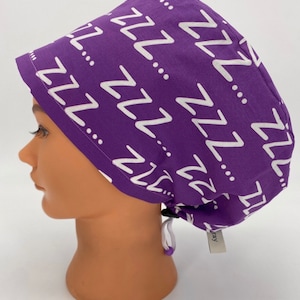 May include: Purple scrub hat with a white 'ZZZ' pattern. The hat has a drawstring and a small tag that says 'ray'.