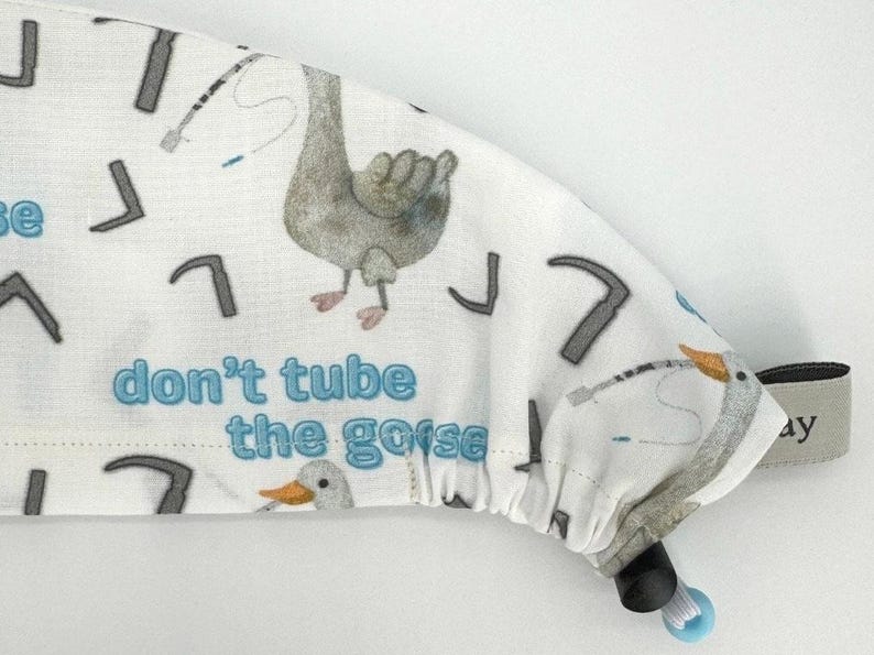 May include: White scrub hat with a blue and gray goose print and the text "don't tube the goose".