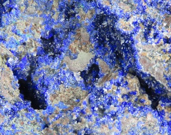 May include: Close-up of a blue and gray mineral specimen with a rough, textured surface. The mineral has a crystalline structure and appears to be a type of azurite.
