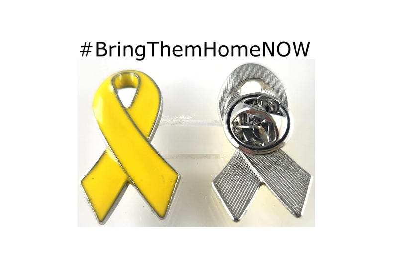 May include: Two yellow awareness ribbon lapel pins. One pin is yellow enamel and the other is silver-toned. Both pins feature a classic ribbon design and have a safety clasp on the back.  #BringThemHomeNOW is displayed above the pins.