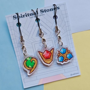 May include: Set of three acrylic charms with black cords and silver-tone clasps. Each charm features a different gemstone design: a green swirl, a red shield, and a blue cluster. The charms are attached to a card that reads "Spiritual Stones".