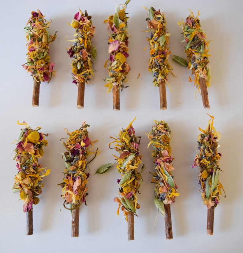 K&ouml;nnte beinhalten: Draufsicht auf zehn R&auml;ucherb&uuml;ndel aus getrockneten Blumen. Die St&auml;be bestehen aus Holzst&auml;ben, die mit getrockneten Blumen und Kr&auml;utern umwickelt sind. Die Blumen sind gelb, orange, rosa und lila. Auf wei&szlig;em Hintergrund angeordnet.