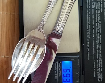 May include: A silver fork, spoon, and knife on a digital scale. The scale reads 69.32 grams. The scale has a capacity of 200 grams and a graduation of 0.01 grams.