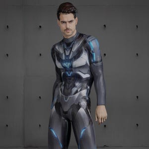 Op de afbeelding: Een persoon draagt een grijs en zwart lang mouw pak met een futuristisch ontwerp. Het pak heeft blauwe accenten en een hoge hals.