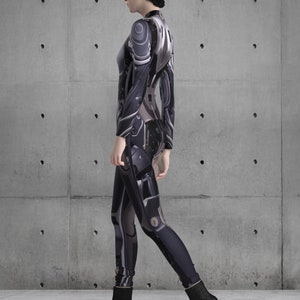 Puede incluir: Un mono futurista ajustado en tonos grises y negros, con intrincados detalles de estilo mec&aacute;nico. El atuendo se combina con botines negros con tac&oacute;n cuadrado. La est&eacute;tica general sugiere un tema de ciencia ficci&oacute;n o cyberpunk.