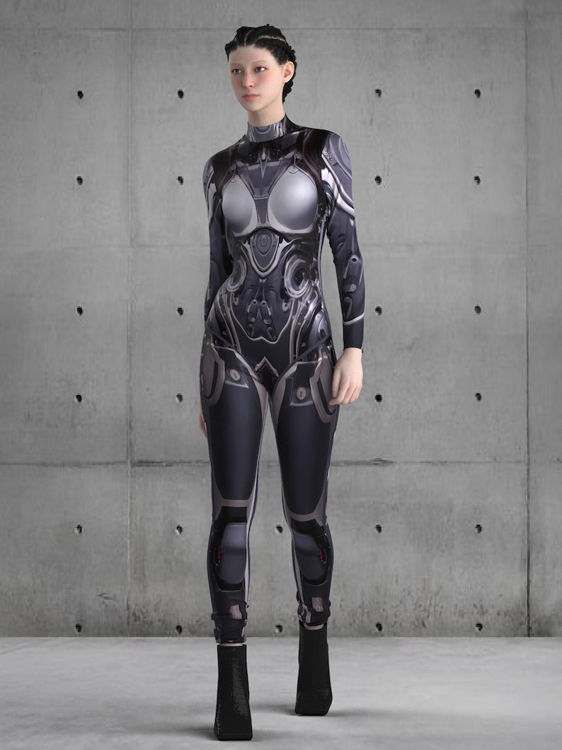 Puede incluir: Mono futurista en negro, gris y plateado. El dise&ntilde;o presenta patrones y detalles intrincados de aspecto mec&aacute;nico, con cuello alto y mangas largas. La modelo lleva botines negros.
