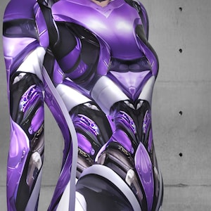 Puede incluir: Un body de color morado y blanco con un dise&ntilde;o futurista y mec&aacute;nico. El traje tiene un cuello alto y mangas largas.