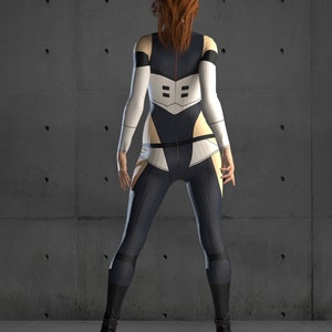 May include: A woman wearing a black and white jumpsuit with a red stripe down the back. She is standing in front of a concrete wall.