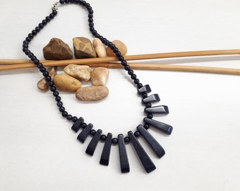 Puede incluir: Un collar de piedras preciosas azul oscuro con un diseño único. El collar presenta una fila de largas cuentas de piedras preciosas puntiagudas que se abren en abanico desde el centro.