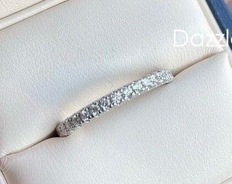 Op de afbeelding: Een dunne zilveren band met kleine heldere stenen in een pavé-setting. De ring zit in een blauwe fluwelen ringdoos.