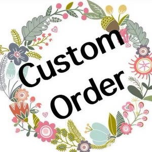 May include: A circular floral wreath with the text "Custom Order" in bold black lettering. The wreath is composed of various flowers and leaves in pink, blue, green, and yellow, set against a white backdrop.