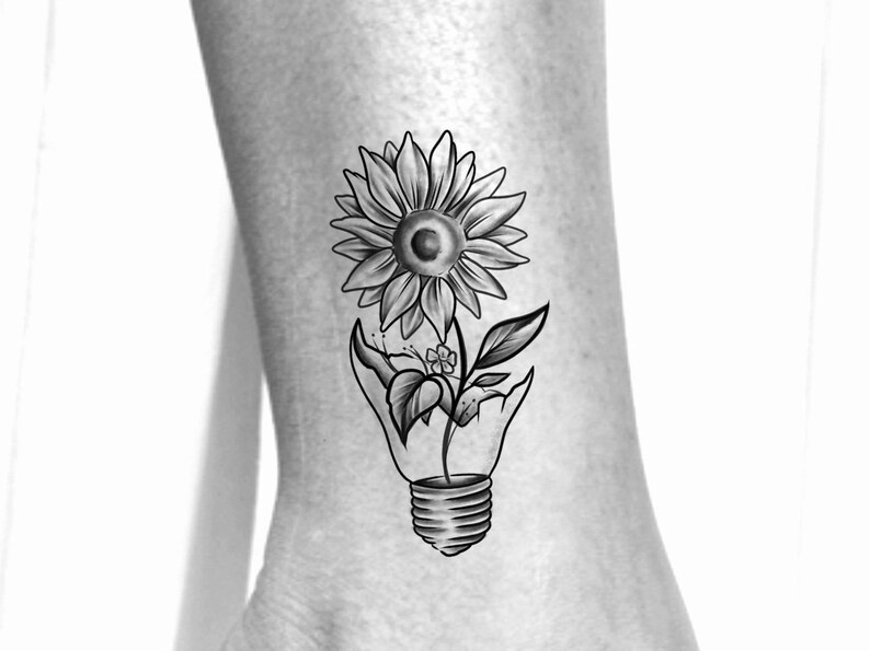 Puede incluir: Dise&ntilde;o de tatuaje en blanco y negro de un girasol que crece fuera de una bombilla rota.